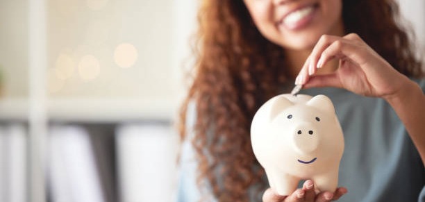 a woman placing coins in her piggy bank
